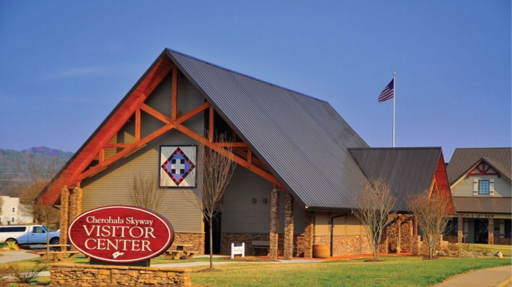 Mountain Visitor Center building with a red sign, steep gray roof, and an American flag