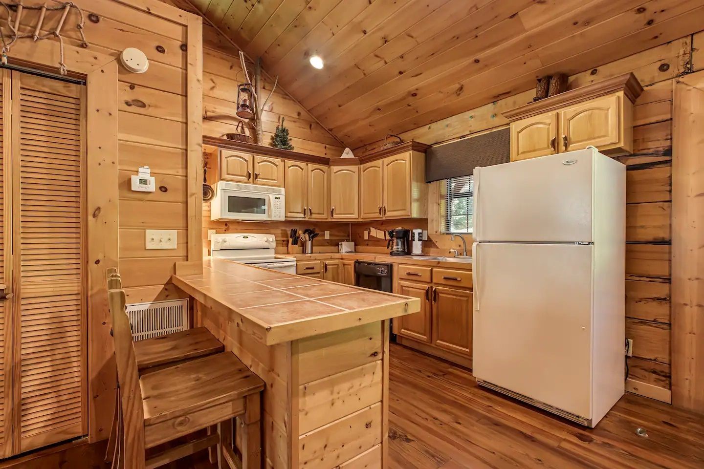 Cozy log cabin kitchen with wood cabinets, white refrigerator, and warm wooden finishes