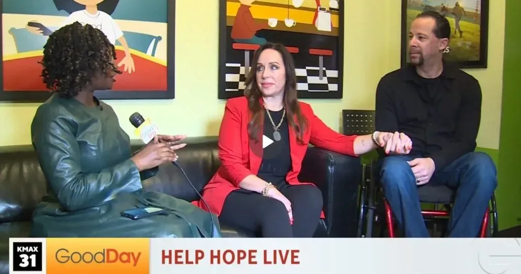 Three people on a couch in a studio, the host interviewing two guests;