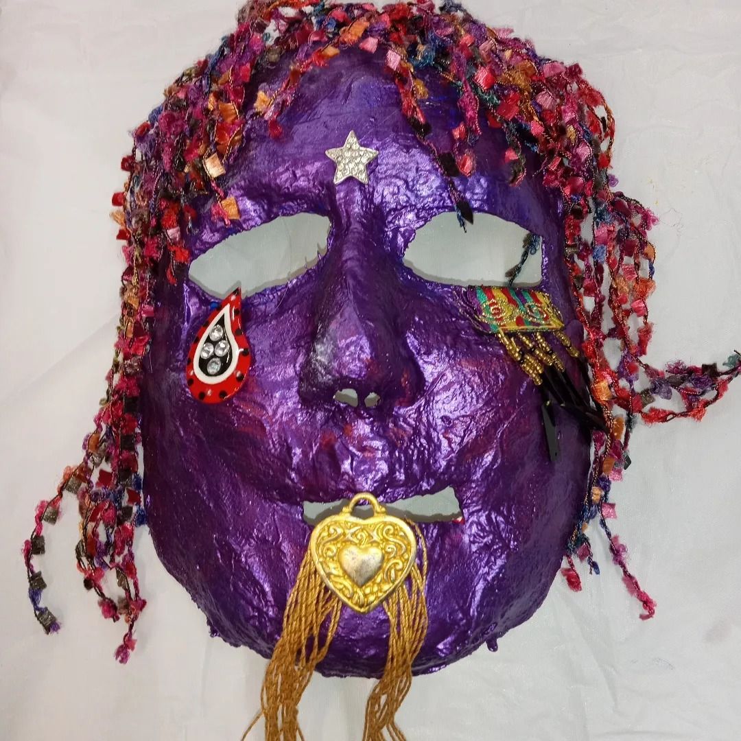 Purple mask with shredded yarn hair, crying tear, star, and gold heart pendant.