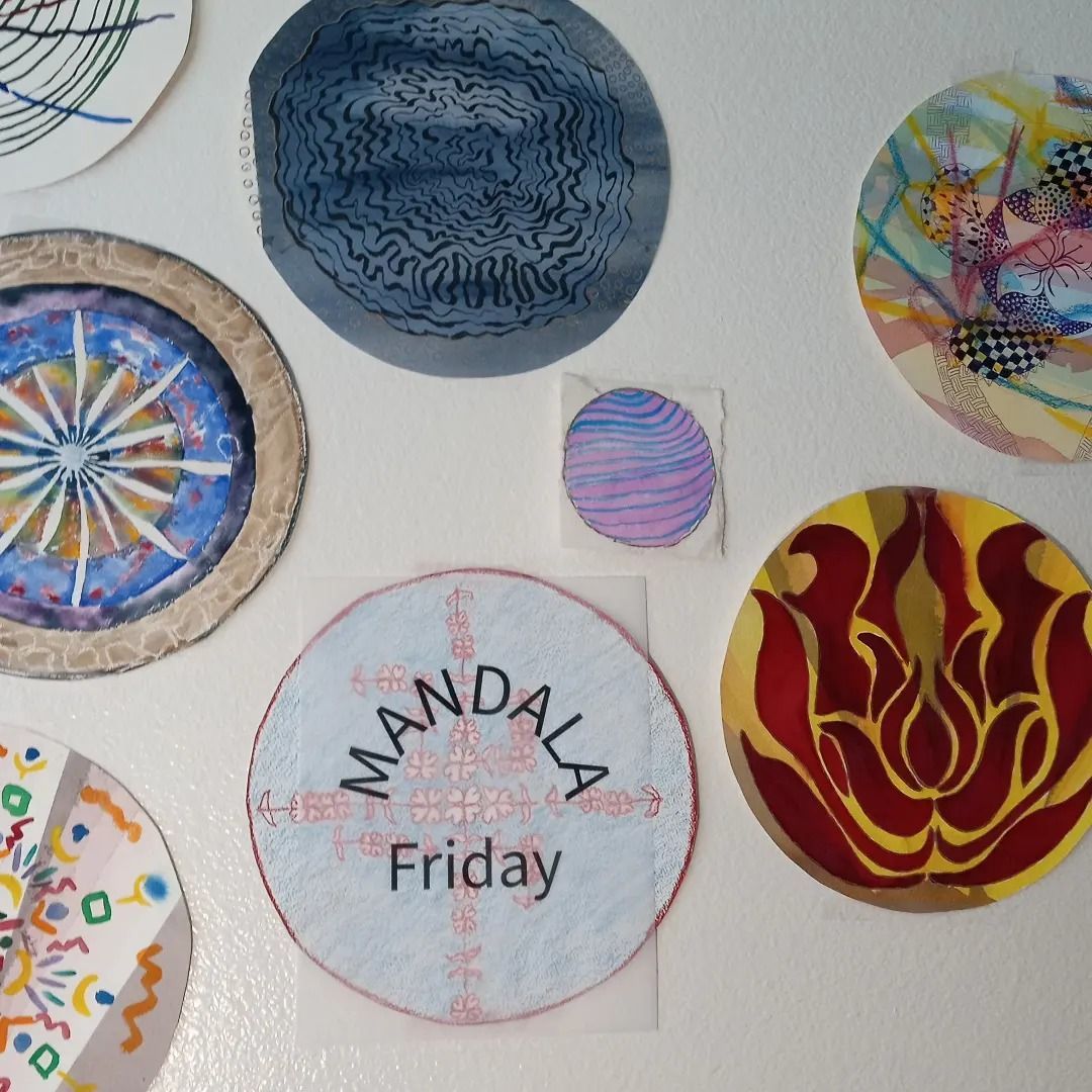 Assortment of circular art, including mandala designs in blue, red, gold, and other colors, affixed to a white surface.