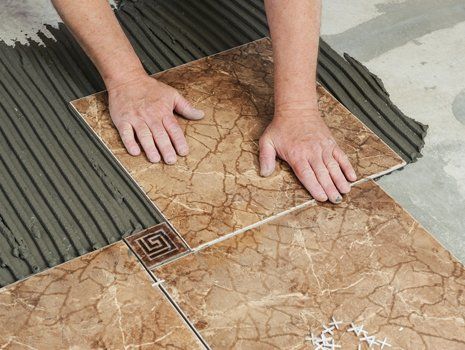 Flooring Installation — Man Placing Ceramic Floor Tile in Concord, NC