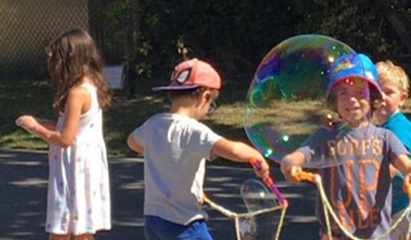 Children playing with bubbles outside on a sunny day.