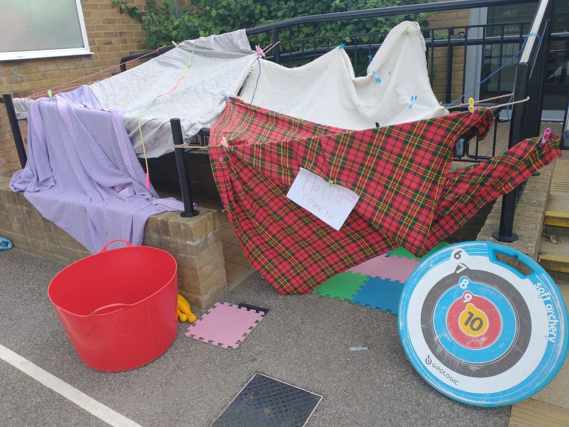 Children making colorful rubber band bracelets outdoors with a container of bands.