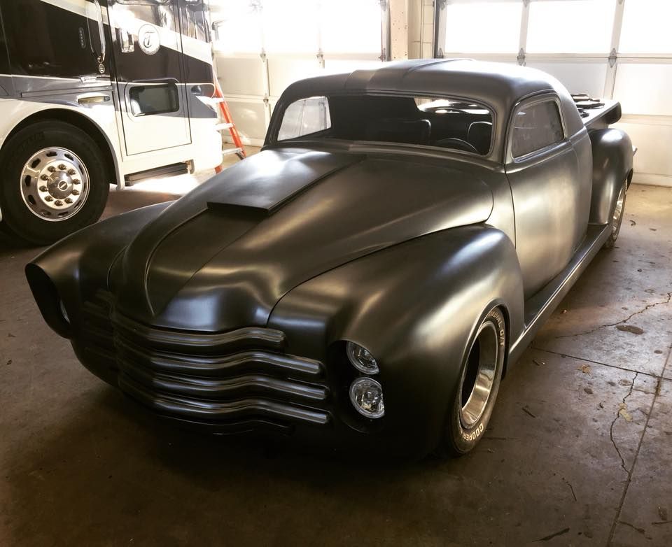 Matte black custom coupe with a low profile in a garage.