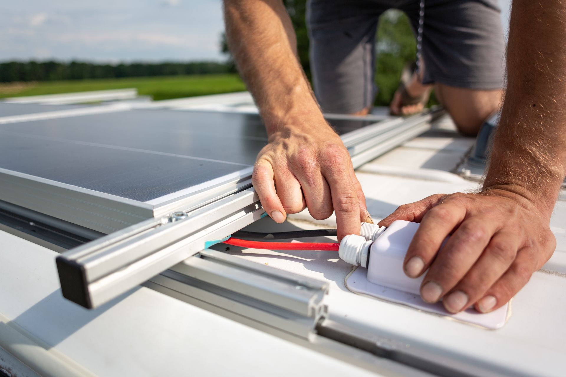 A man is installing solar panels on the roof of a van.