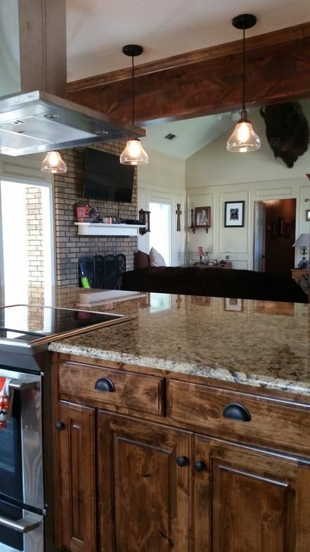 Kitchen with granite countertop, wooden cabinets, and hanging pendant lights.