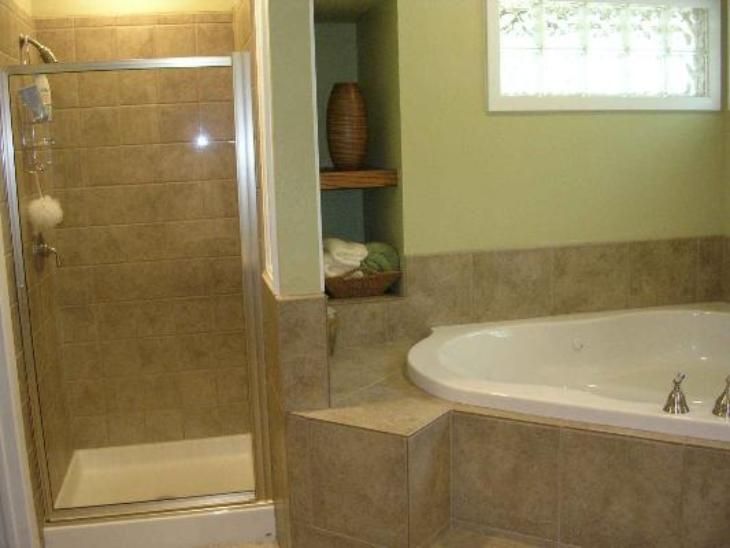 Bathroom with tiled shower and tub, built-in shelving, and a small window.