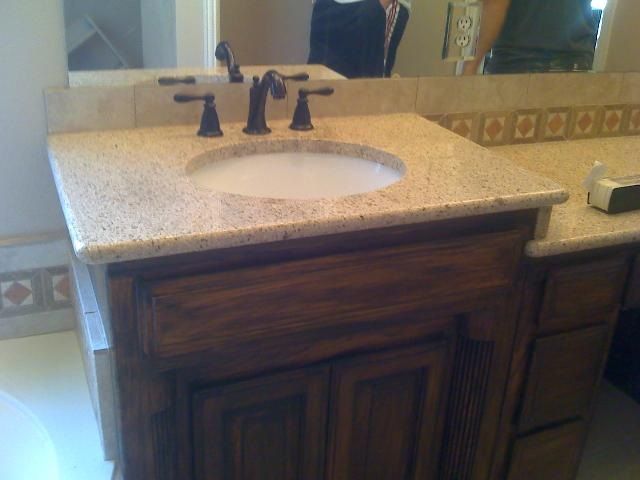 Bathroom vanity with granite countertop, dark wood cabinets, and bronze faucet.