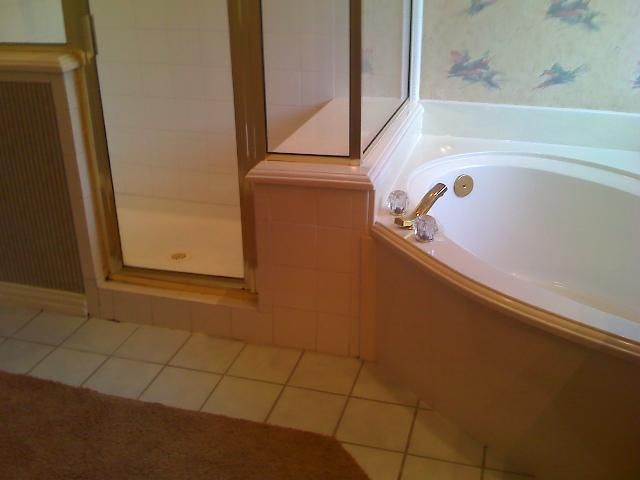 Corner bathroom with a shower and tub, light beige walls and floor tiles.