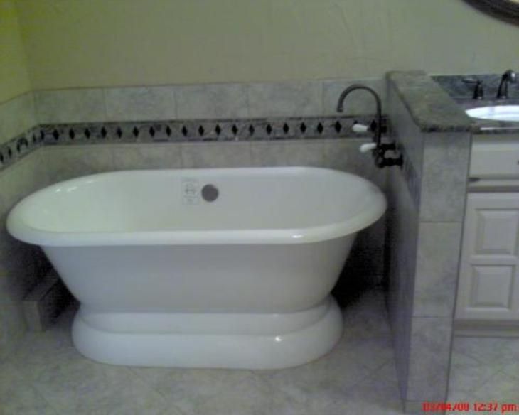 White oval freestanding bathtub in a bathroom with tile.