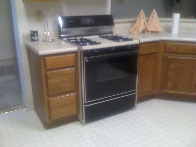 Kitchen with a black oven, gas stovetop, and wooden cabinets.