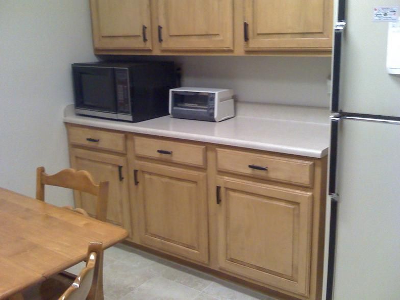 Kitchen cabinet and countertop with a microwave, toaster, and refrigerator.