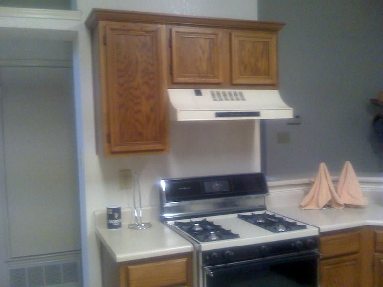 Kitchen with wood cabinets, stove, and range hood. A countertop with folded napkins is visible.