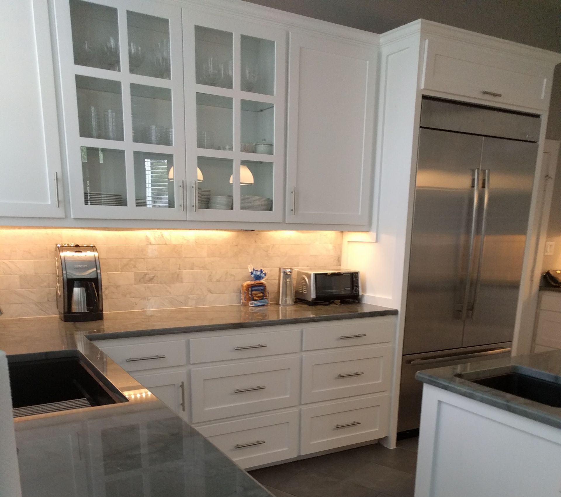 White kitchen cabinets with a stainless steel refrigerator, countertops, and appliances.