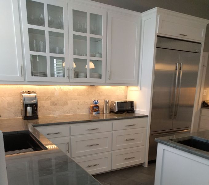 White kitchen cabinets with a stainless steel refrigerator, countertops, and appliances.