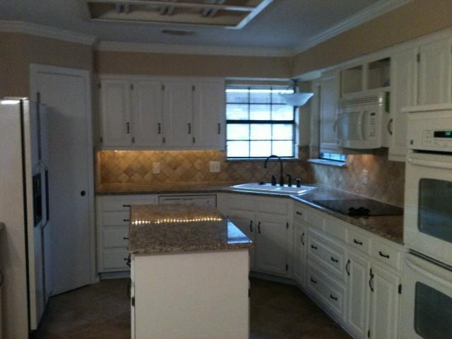 White kitchen with granite countertops, island, and appliances.
