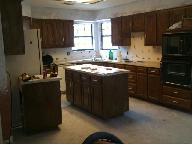 Kitchen with brown cabinets, island, and appliances, showing signs of renovation.