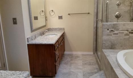 Bathroom with granite countertop, wooden vanity, tiled shower with glass door, and a soaking tub.