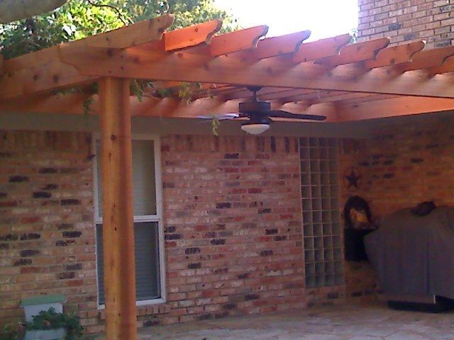 Pergola over a brick patio with a ceiling fan.