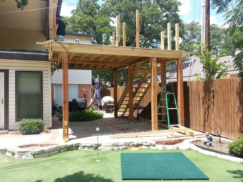 Construction of a wooden deck with stairs in a backyard with a putting green.