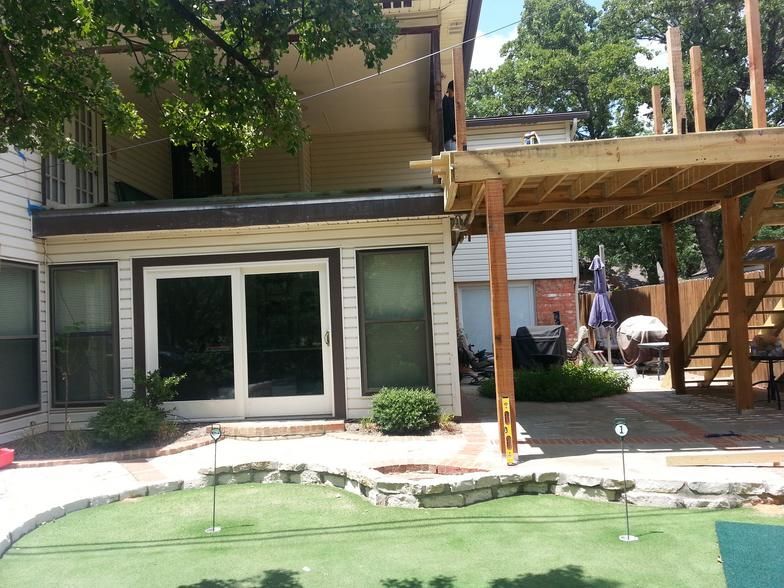 Backyard with putting green, house with deck, and sliding glass doors.