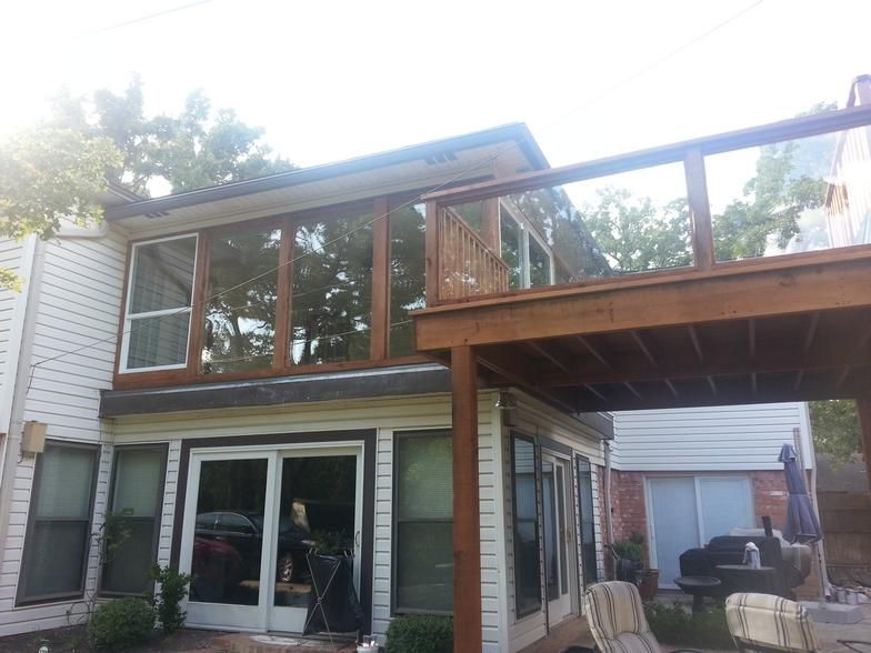 Exterior of a two-story house with a wooden deck and large windows.