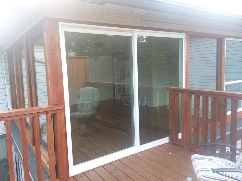 Deck with sliding glass door, wooden railing, and a glimpse of the interior.