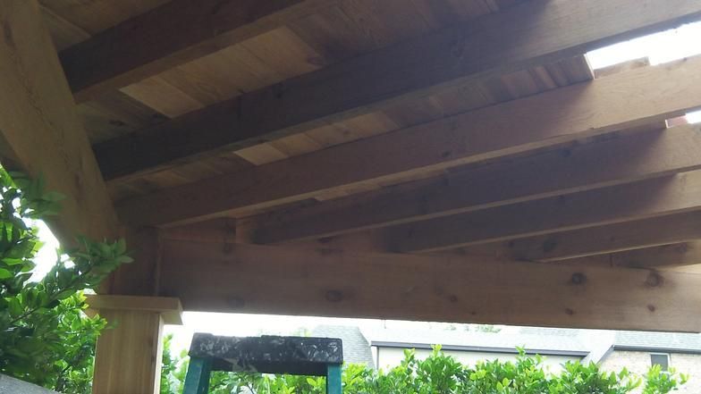 Wooden pergola roof with supporting beams and posts.