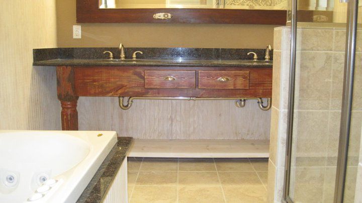 Bathroom with a dark granite countertop on a wood vanity. There's a jacuzzi and a shower in the frame.