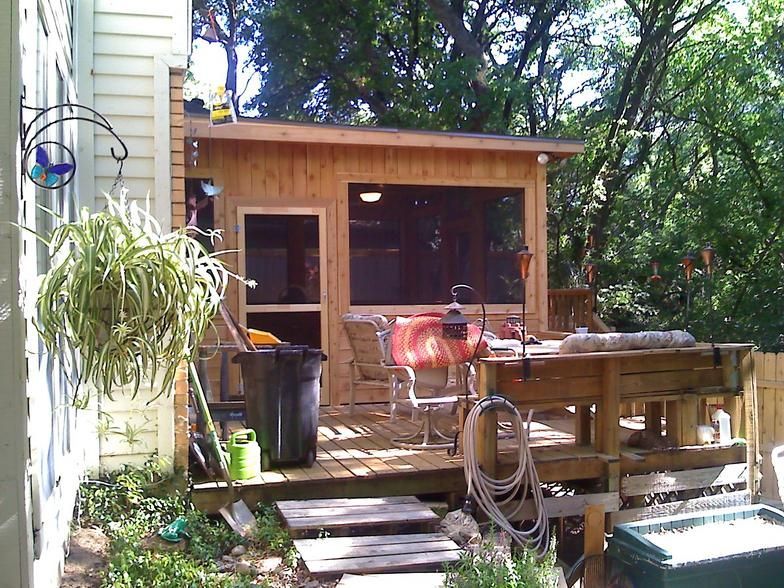 Wooden backyard deck with screened porch, table, chairs, and garden items.