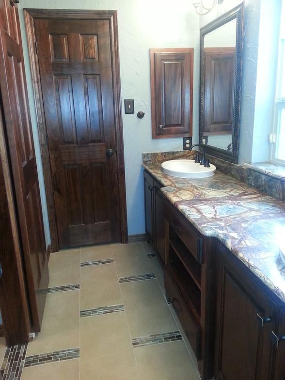 Bathroom with dark wood vanity, door, and trim. Granite countertop, round sink, and patterned floor.