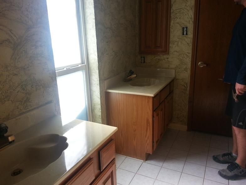 Bathroom with two vanities, window, and person standing near a door.