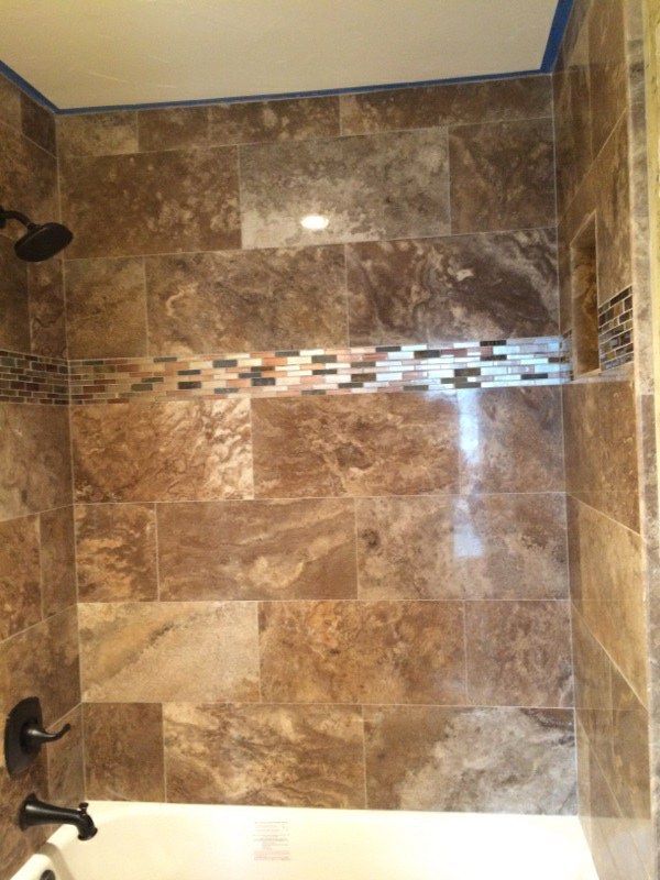 Brown tiled shower with a decorative mosaic tile strip and built-in niche.
