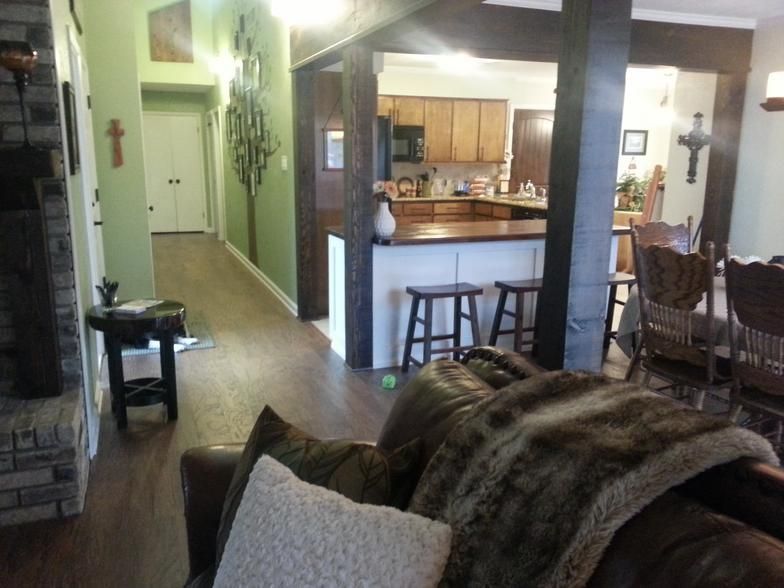 Living room with dark wood floors, fireplace, and open kitchen with bar stools.