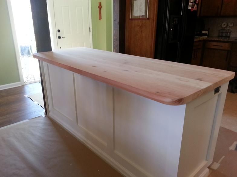 White kitchen island with a light wooden countertop.