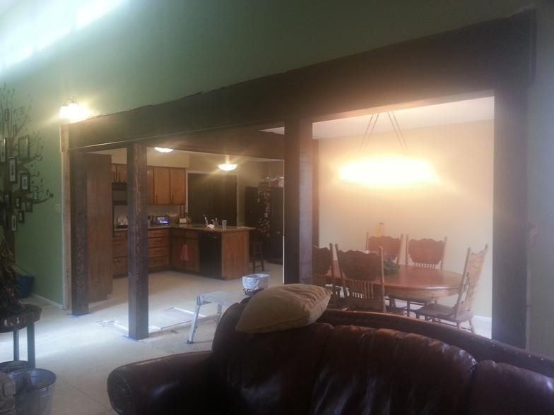 Living room with dark wood beams defining spaces for kitchen and dining area.