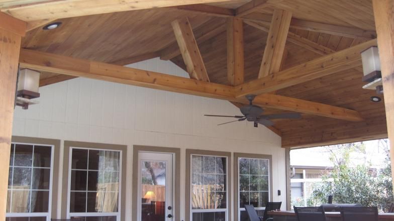 Wooden patio roof with exposed beams, recessed lighting, and a ceiling fan.