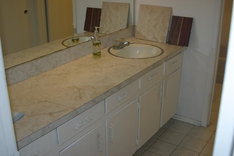 Bathroom vanity with marble countertop, two sinks, white cabinets, and large mirror.