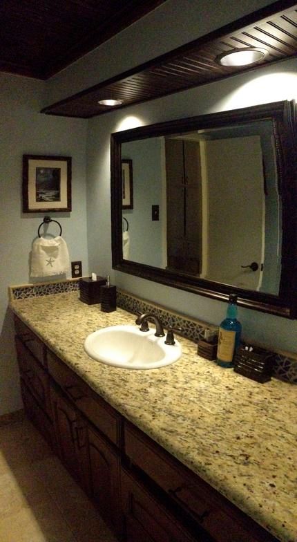 Bathroom with a long vanity, granite countertop, large mirror, and dark wood trim.