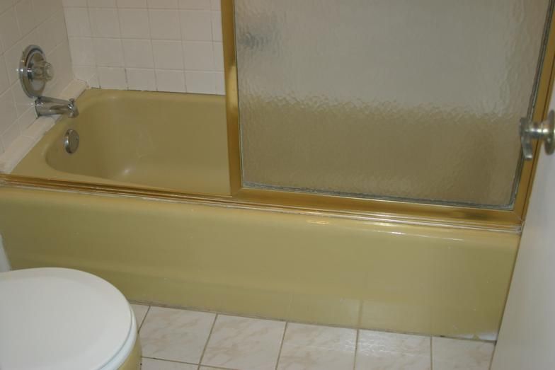 Yellow bathtub with a frosted glass shower door, in a bathroom.
