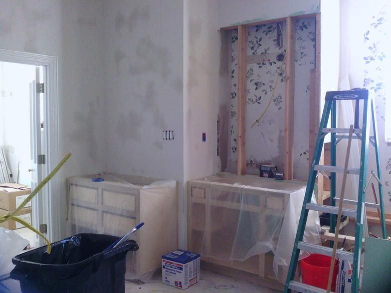 Bathroom under construction with exposed framing, unfinished cabinetry, and a ladder.
