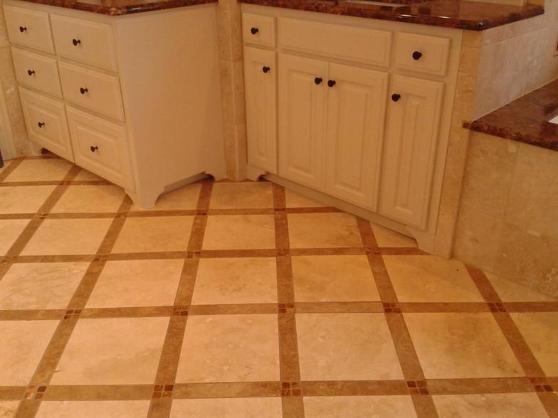 Bathroom with tiled floor in a grid pattern and white cabinets with dark hardware.