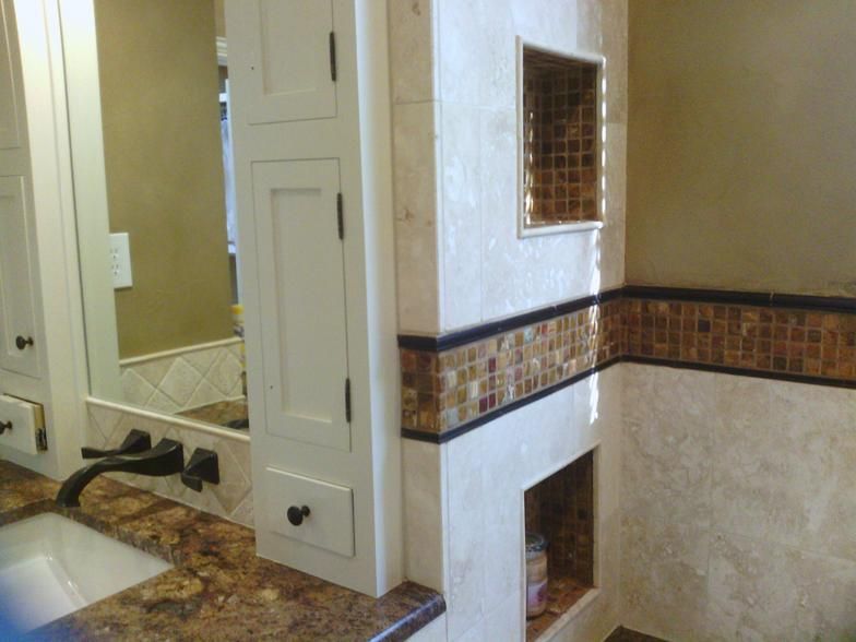 Bathroom with white cabinets, stone countertop, tile shower with mosaic accent, and neutral-colored walls.