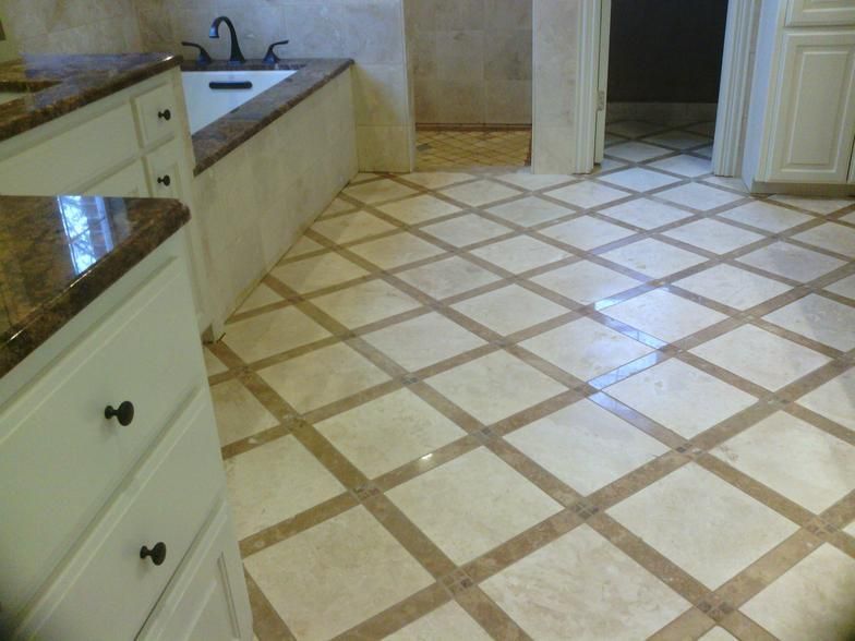 Bathroom with white cabinets, granite countertops, and a diagonally tiled floor in cream and brown tones.