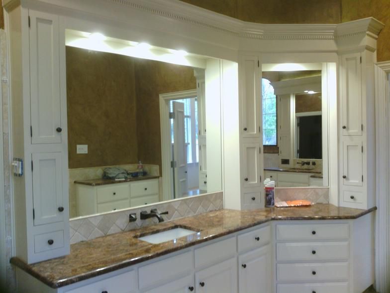 White bathroom vanity with granite countertop, mirror, and cabinets.
