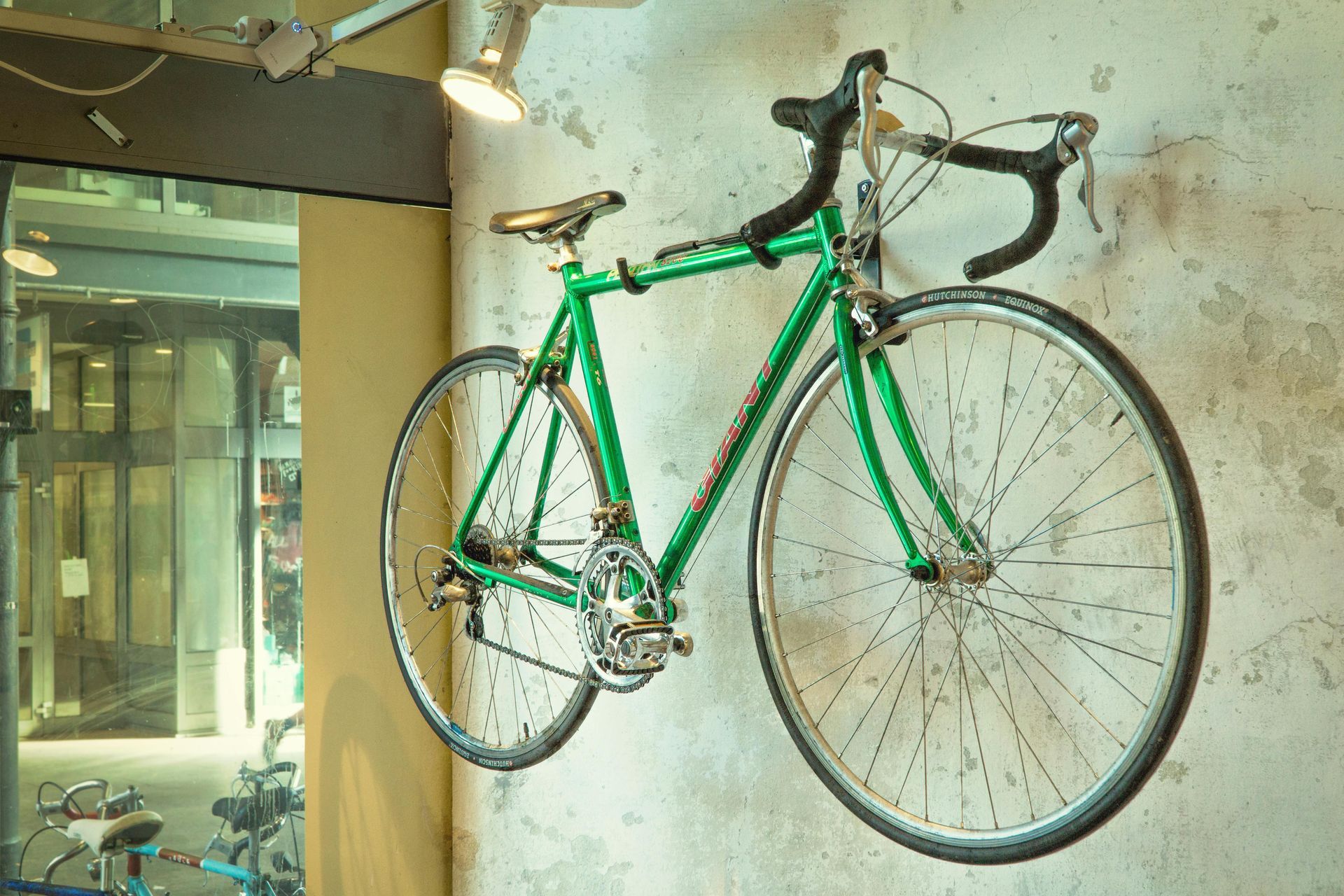 A green bicycle is hanging on a wall