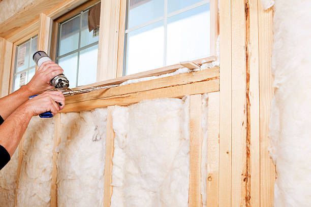 Sealing a wooden window frame with spray foam insulation.