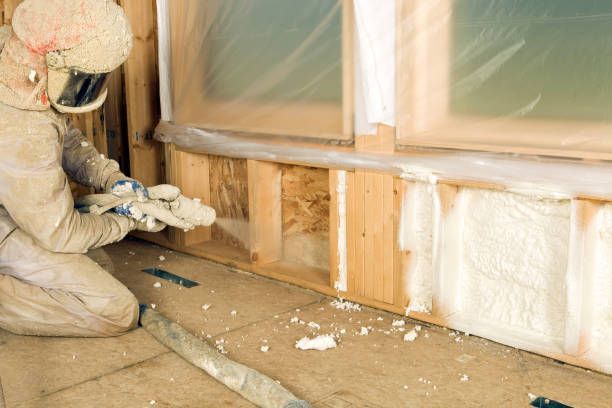 Contractor applying spray foam insulation to a wall base.