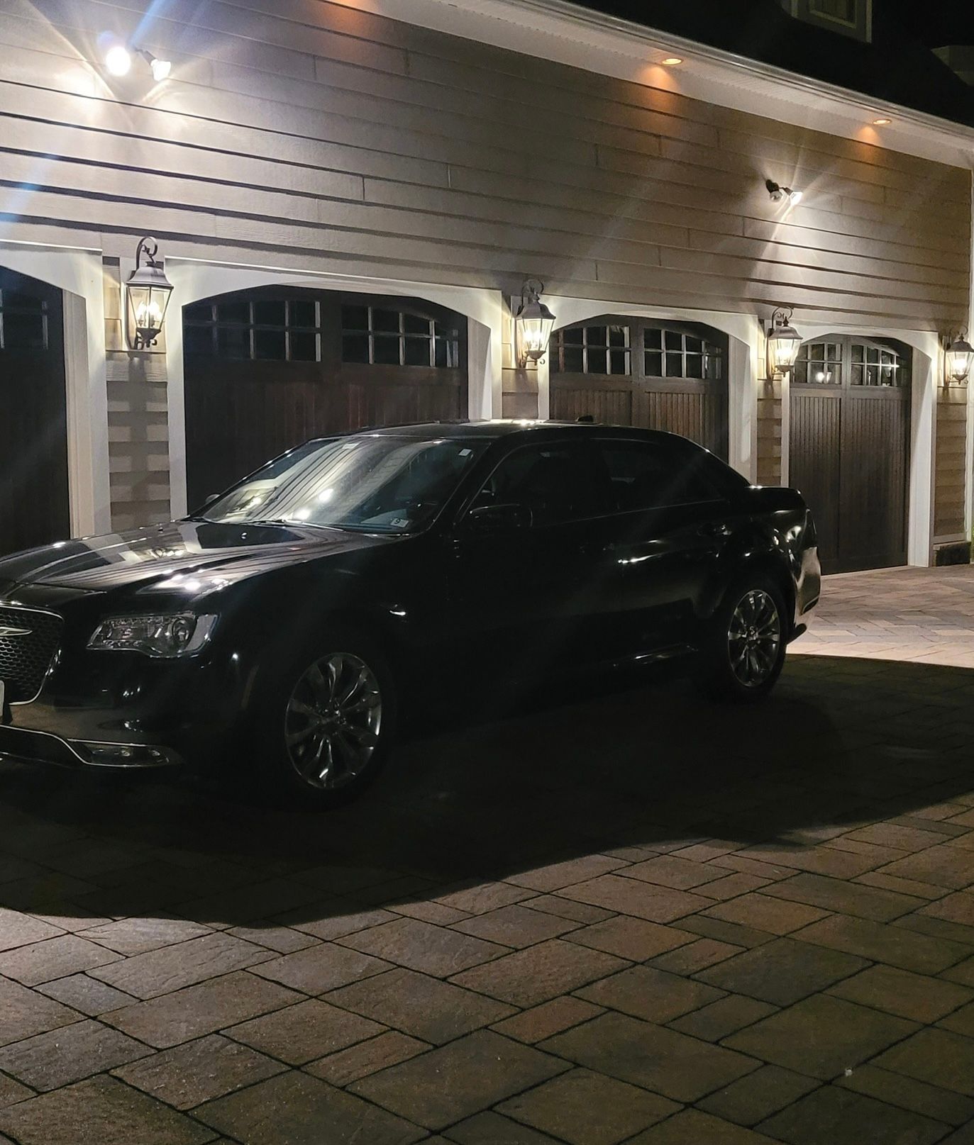 A black car is parked in front of a garage at night